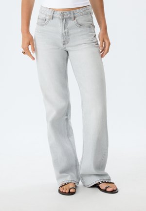 Light gray denim jeans with a relaxed fit, high waist, five-pocket design, and subtle distressed details. Paired with black flat sandals.