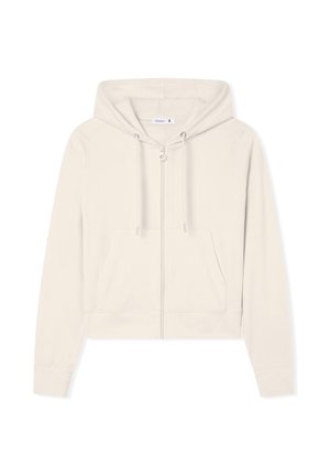 Przycięta, jasnobeżowa bluza z kapturem, wykonana z miękkiego materiału, z suwakiem z przodu, dwiema kieszeniami z przodu oraz sznurkami do regulacji na kapturze.