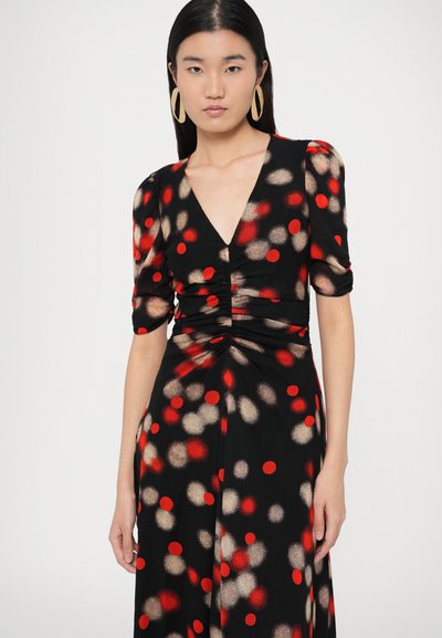 Musta mekko, jossa on V-pääntie, lyhyet röyhelöhihat ja vyötäröllä rypytys, sekä punainen ja kultainen pistekuvio teksturoidulla kankaalla.