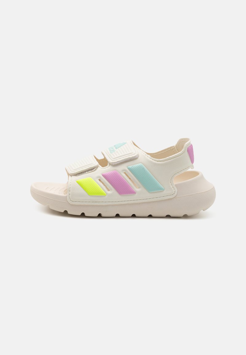 Λευκή σαγιονάρα με ιμάντες Velcro, πολύχρωμες λεπτομέρειες σε νεον πράσινο, ροζ και μπλε, με υφασμάτινη επιφάνεια και ανθεκτική καουτσούκ σόλα.