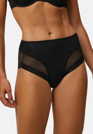 Mujer vistiendo ropa interior negra de cintura alta con paneles de malla transparente en los costados, combinada con un sujetador negro a juego, torso visible.