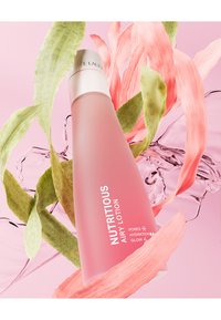 Rosa flaska av Estee Lauder Nutritious Airy Lotion, med en böjd form, silverlock och vit text, omgiven av gröna och rosa blad.