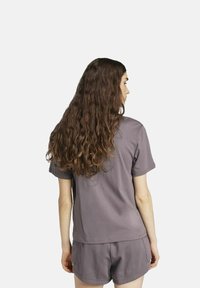 Camiseta de algodón morada con mangas cortas, combinada con pantalones cortos de algodón a juego. La tela tiene una textura suave y un corte holgado.