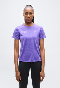 Μωβ αθλητική κοντομάνικη μπλούζα με στρογγυλή λαιμόκοψη και διακριτική υφή· διαθέτει λογότυπο σε ανοιχτό γκρι στο μπροστινό μέρος. Μαύρο εφαρμοστό παντελόνι.