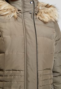Pufferjack in licht bruin met een gestructureerde synthetische buitenkant, voorzien van een nepbont kraag, drukknoopsluiting en gestikte accenten.