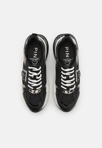 Sneakers atletiche nere realizzate in mesh e materiali in pelle sintetica; presentano lacci bianchi, un logo prominente e un motivo testurizzato.