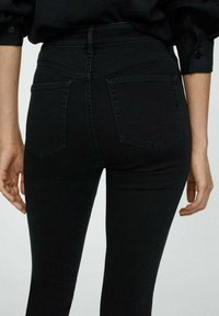 Mustat korkeavyötäröiset farkut, joissa on sileä denim-pinta, kaksi takataskua ja muotoiltu siluetti.