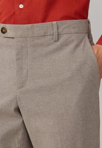 Pantalones cuadros grises con un tejido texturizado, que presentan bolsillos laterales y un cierre de botón. Combinados con una camisa roja.