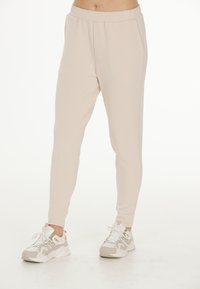 Ljusbeige joggers i mjukt material med elastisk midja, har en taperad passform och sidofickor. Matchas med vita sneakers.