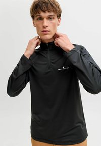 Mustast, lukustatava pikkade varrukatega pullover, mis on valmistatud kergest ja siledast kangast. Rinnal on väike "TECH FUSION" logo ja sobitatud mansetid.