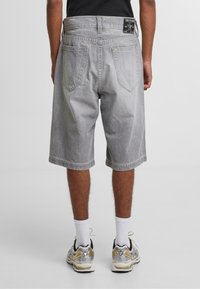 Szare dżinsowe szorty o luźnym kroju, pięć kieszeni i haftowany wzór. Zawierają metkę w pasie oraz podwinięte nogawki.