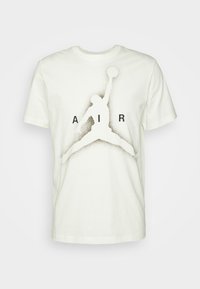 Vit bomullströja med en svart silhuett av en hoppande figur med en basketboll, tillsammans med texten "AIR" i fet stil.