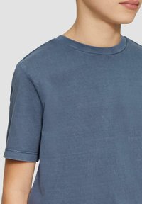 Korte mouwen blauwe katoenen t-shirt met een ronde halslijn en subtiele textuur. Schone stiksels langs de mouwen en de zoom.