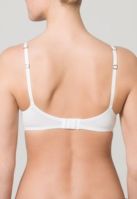 Witte bh met verstelbare bandjes, glad materiaal, sluiting met haakje op de rug en een minimalistisch ontwerp. Geen extra patronen of versieringen.