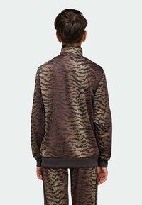 Hnedo-béžová bunda na zips s tigrovaným vzorom, vybavená vysokým golierom a rebrovanými manžetami, vyrobená z hladkej, ľahkej látky.