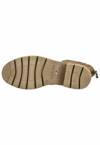 Semelle de botte en caoutchouc beige clair, dotée de rainures multidirectionnelles pour une meilleure traction. Surface texturée avec un logo subtil et une étiquette de pays.
