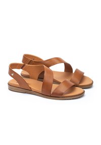 Sandalias de cuero marrón con suela plana, con correas entrelazadas y contrafuerte en el talón. Textura suave y acentos de hardware mínimos.