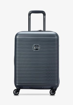 Valigia in policarbonato grigia con design testurizzato e a righe, manico retrattile e quattro ruote nere per la mobilità. Dotata di un meccanismo di blocco.