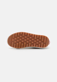 Talpa de sneaker albă cu o suprafață robustă din cauciuc de culoare maro, având un model hexagonal și linii de tracțiune solide. Accent roșu la călcâi.