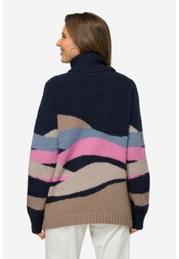 Pull en maille épaisse bleu marine, avec un col haut et des motifs en vagues audacieux en beige, bleu clair et rose. Poignets et ourlet côtelés.