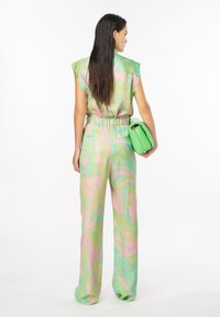 Completo a due pezzi con un motivo astratto verde e rosa, realizzato in tessuto leggero. La parte superiore ha una vestibilità rilassata e maniche ampie; i pantaloni coordinati sono larghi.