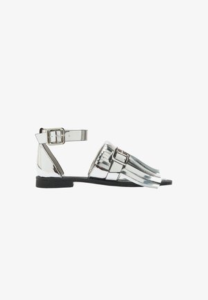 Metaliczne srebrne płaskie sandały z otwartym palcem i paskiem na kostce, z zapięciem na klamrę i teksturowanym frędzlem.