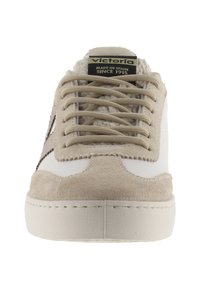 Sneaker con toma in pelle bianca, dettagli in suede beige, lacci rotondi e suola in gomma texturizzata. L'etichetta riporta "Victoria", indicando origine spagnola.