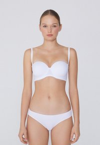 Biały stanik z gładkimi, formowanymi miseczkami i cienkimi ramiączkami. Pasujące bikini w jednolitej bieli. Prosty, bezszwowy design bez zdobień.
