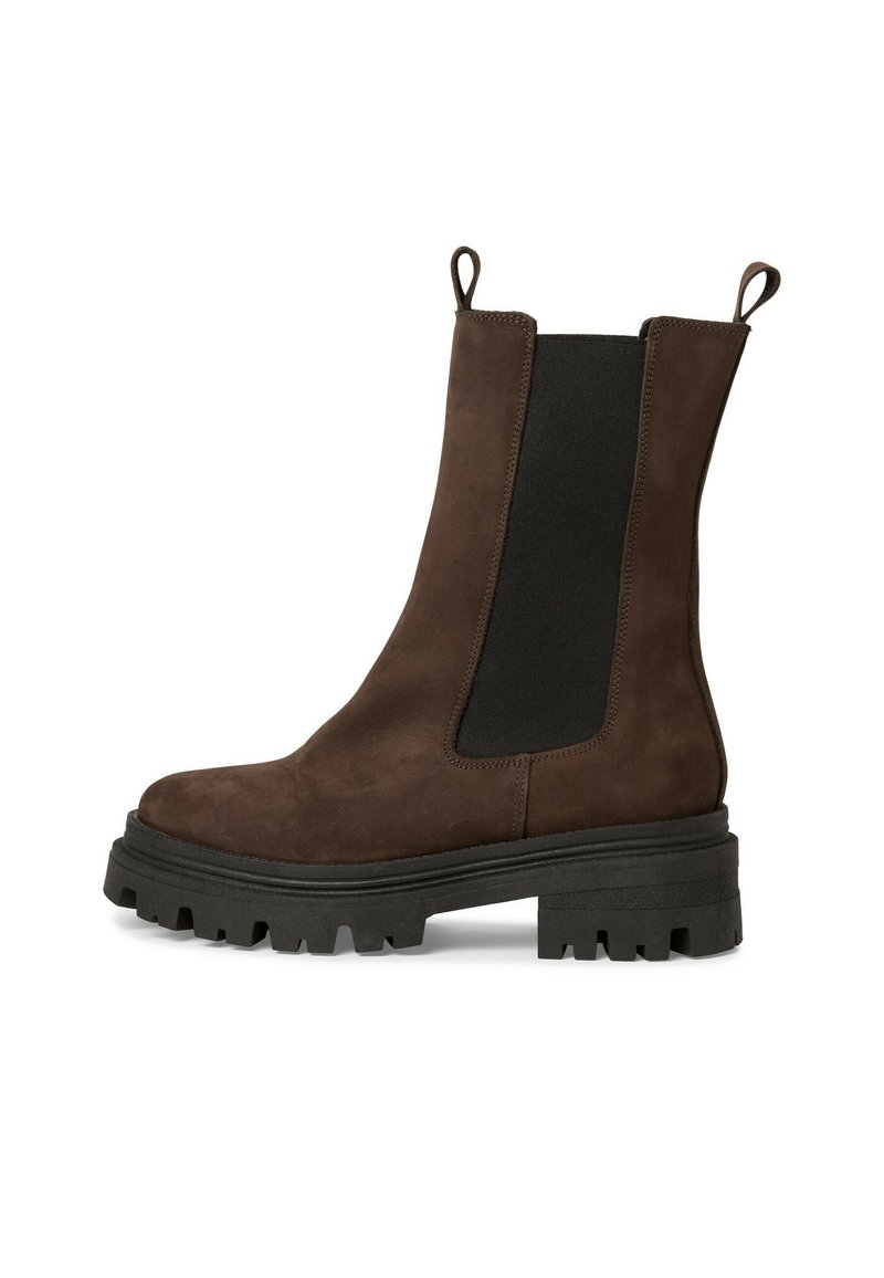 Bottines en suède marron avec des panneaux latéraux élastiques, des languettes de tirage et des semelles en caoutchouc noir épaisses. Elles présentent une texture lisse et un design à bout rond.