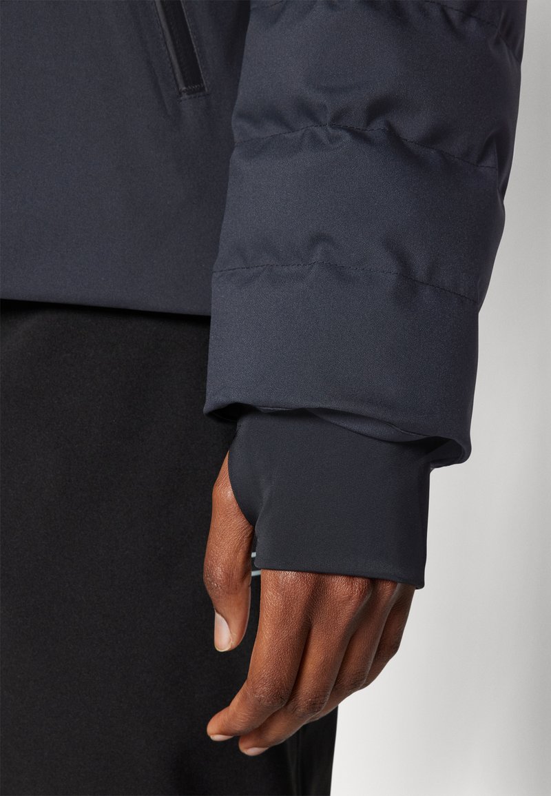 Marineblauer Pufferjackenärmel mit engem, elastischem Bündchen und glatter Textur. Verfügt über Steppung und ein schlankes Design mit teilweise sichtbarer Hand.