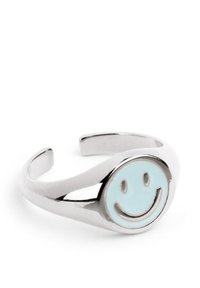 Anillo de metal en tono plateado que presenta una cara sonriente redonda de color azul menta en el centro. Diseño de banda abierta ajustable con un acabado pulido.