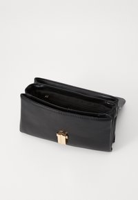 Clutch bag in pelle nera con finitura testurizzata e una chiusura geometrica dorata. L'interno presenta due scomparti con una tasca con zip.