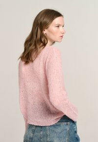 Helles rosa, flauschiges Strickpulli mit lockerer Passform. Rundhalsausschnitt, leicht verkürzter Rücken, lange Ärmel und eine weiche, durchsichtige Textur.