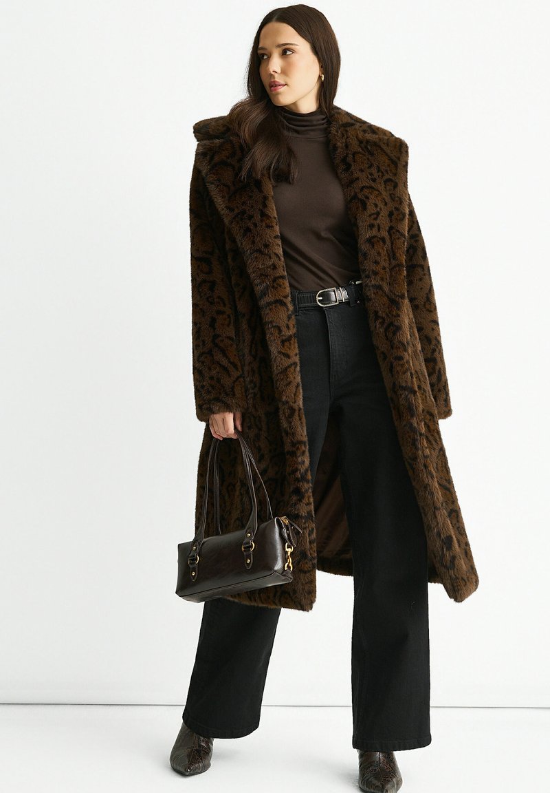 Brown faux fur coat with leopard print, wide lapels, and a loose fit, paired with black high-waisted trousers and a small brown handbag.