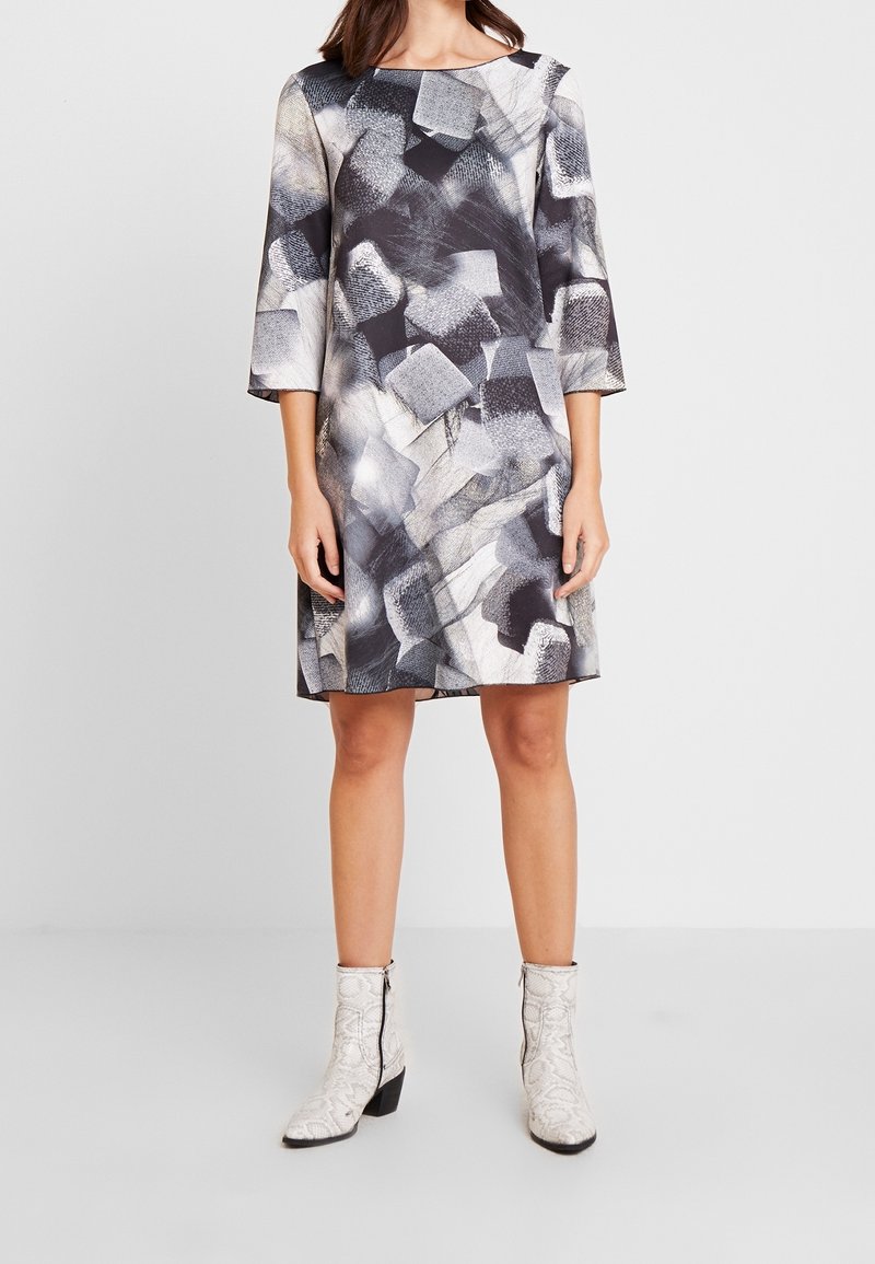 Vestido de manga larga con un patrón abstracto en gris, negro y beige. Confeccionado en tela suave, tiene un corte suelto y cuello redondo.