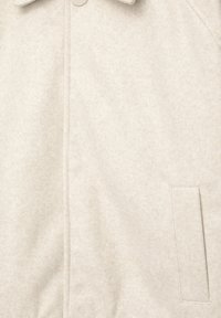 Beige frakke lavet af filtmateriale, med krave, frontlukning med knapper og en sidelomme med en subtil tekstur.