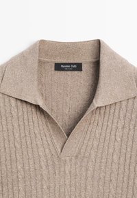 Maglione beige a trecce con ampio colletto e scollo a V, caratterizzato da un'etichetta nera Massimo Dutti cucita all'interno del collo.