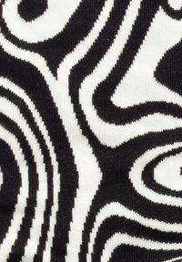 Abstrakter schwarz-weißer Stoff mit wellenförmigen, wirbelnden Mustern. Die Textur sieht gestrickt aus, mit kontrastierenden Farben und klar definierten Kanten.