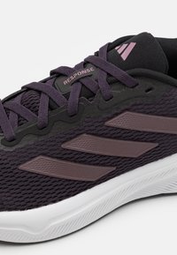 Paarse sportieve schoen met een bovenwerk van mesh, textuurdetails en drie kenmerkende strepen in een donkerdere tint. Voorzien van een witte zool met grippatroon.