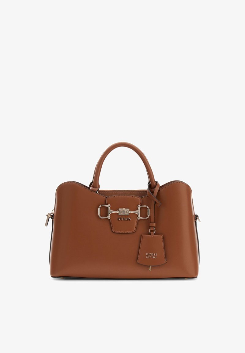 Sac à main en cuir marron avec deux poignées supérieures, fermoir décoratif argenté et étiquette suspendue embossée de "GUESS EST 1981".