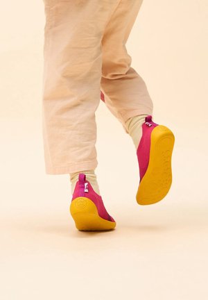 Children's slip-on shoes with a bright pink fabric upper and yellow rubber sole, featuring a zip accent on the heel for easy wear.