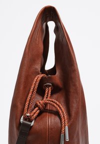 Rjava usnjena torba z gladko teksturo, ki ima edinstven dvojni otvor in oranžne vrvice, ki so zavarovane s srebrom.