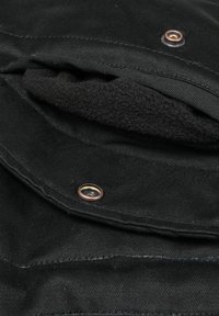Black fabric pocket with a soft, black fleece lining, featuring a copper-colored snap button as a closure detail.