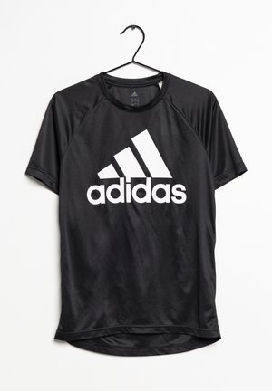 Czarna sportowa koszulka Adidas z krótkim rękawem z białym logo i napisem, wisząca na czarnym metalowym wieszaku na białym tle.