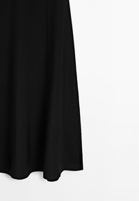 Gonna nera con un design svasato, caratterizzata da una texture liscia e un tessuto a righe sottili. L'orlo ha un delicato bordo curvo per una silhouette fluida.