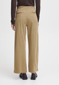 Pantalon à jambes larges à motif à carreaux, avec un schéma de couleurs jaune et marron, doté de deux poches arrière et d'une coupe ajustée.