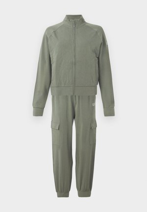 Olíva zöld tréningruha szett, amely egy cipzáras dzsekit tartalmaz, steppelt mintával, valamint szűkülő nadrágokat, amelyek rakományzsebekkel és rugalmas mandzsettákkal rendelkeznek.