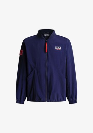 Navyblauw jack met rits en het Red Bull Racing-logo op de borst, een rode ritsluiting en een patch op de linker mouw, met elastische boorden en zoom.