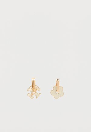 Cercei hoop din aur cu pandantive crem în formă de floare și trifoi, pe un fundal alb.