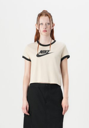 Kermakohvane lühikeste varrukatega t-särk musta ääre ja varrukate siseküljega, ees keskel on tähelepanuväärne must Nike logo.